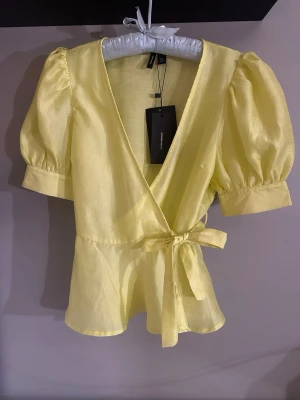 Gul omlottblus med puffärm - Säljer en ljusgul omlottblus från Vero Moda med puffiga ärmar i stl. XS