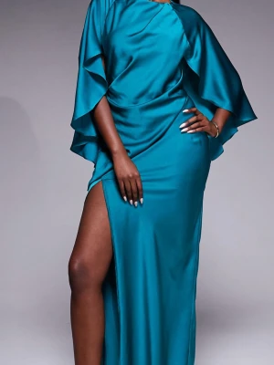 Turkos långklänning med slits - Säljer en elegant turkos långklänning i glansigt satintyg. Klänningen har vida, fladdriga ärmar, hög slits på benet och öppen rygg. Perfekt för dig som vill sticka ut med en unik och lyxig look.