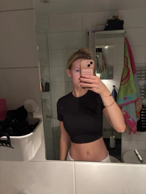 Svart croppad topp från Primark - Säljer en svart croppad topp från Primark i ribbat material. Toppen har korta ärmar, öppen rygg och knytband bak som ger en snygg och trendig look. Perfekt för dig som gillar unika detaljer och vill sticka ut lite extra.