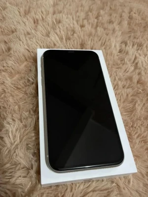 iPhone 11 - Apple iPhone 11 i vitt utförande. Telefonen har dubbla kameror och stor skärm. Baksidan är kraftigt sprucken och har tydliga skador, särskilt vid laddningsporten. Perfekt för reservdelar och funkar men den är lite lagig.