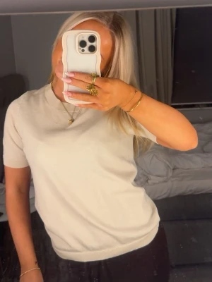 Tunn stickad t—shirt - Enkel och stilren beige stickad t-shirt med rund hals från Lindex i storlek XS. Perfekt att matcha med jeans eller kjol för en clean look. Använd få gånger så den är i väldigt väldigt bra skick!