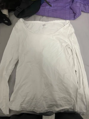 Vit långärmad topp från 157 - En enkel och stilren vit långärmad topp från 157 i storlek XL. Tillverkad i mjuk bomull med lite stretch för extra komfort. Toppen har en rundad halsringning och är perfekt att matcha med jeans eller kjol för en clean look.