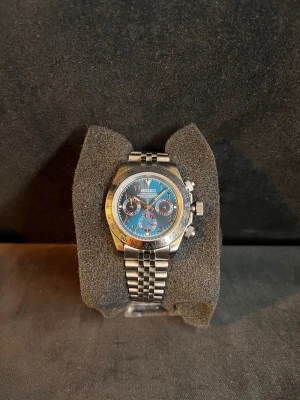 Seiko Mod - Klocka - Jättefin hel-stål ”Seiko mod” klocka med en spännande urtavla vilken passar dig som är ute efter något utstickande och spännande.  Byggd för hand och är helt oanvänd.  Klockan har;  *Handbyggd *Seikos egna VK63 urverk *Halv mekanisk *Blå urtavla med röda detaljer *39mm boett *jubilee armband ingår! *Arabiska siffror *Fungerande kronograf