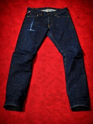 Ralph Lauren jeans - Säljer ett par mörkblå jeans från Denim & Supply Ralph Lauren. Klassisk femficksmodell med snygga kontrastsömmar och en liten detalj med amerikansk flagga vid fickan. Jeansen har rak passform och är tillverkade i slitstarkt bomullsdenim.