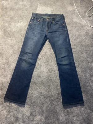 Faded Jeans - Klassiska blå Levi's 507 jeans med raka ben och har en flared/bootcut modell. Jeansen har en snygg mörkblå tvätt och detaljer i kopparfärgade nitar. Tillverkade i slitstarkt denimtyg av bomull. Perfekta för dig som gillar tidlös och enkel stil.