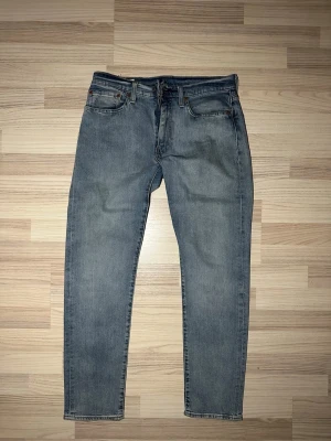 Levi's 502 ljusblå jeans W31 L32 - Säljer ett par klassiska Levi's 502 jeans i ljusblå tvätt. De har rak passform, fem fickor och den ikoniska läderlappen bak i midjan. Jeansen är tillverkade i slitstarkt denim och har normal midja. Perfekta för en avslappnad och stilren look.