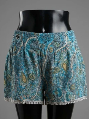 Blå paisleymönstrade shorts Bali - Säljer ett par blå paisleymönstrade shorts från Collection Bali. De har hög midja med resår, lös passform och fina virkade detaljer längst ner. Materialet känns lätt och luftigt, perfekt för varma dagar. Mönstret är färgstarkt med inslag av gult och vitt.