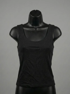 Svart linnetopp från Gina Tricot - Säljer en svart, enkel och stilren linnetopp från Gina Tricot, kollektionen Elevated Basics. Toppen är ärmlös med breda axelband och har en rak, klassisk form. Materialet är 95% ekologisk bomull vilket gör den mjuk och skön mot huden.