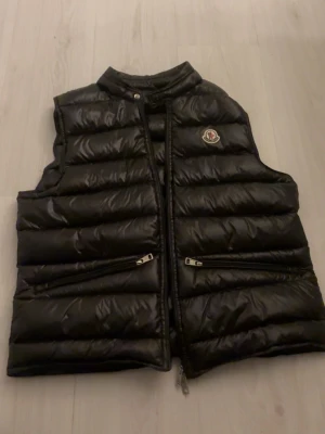 Svart dunväst från Moncler - Säljer en svart dunväst från moncler , den är helt oanvänd. Scan funkar. Den är storlek S och säljer den då den är för liten. Pris kan diskuteras.