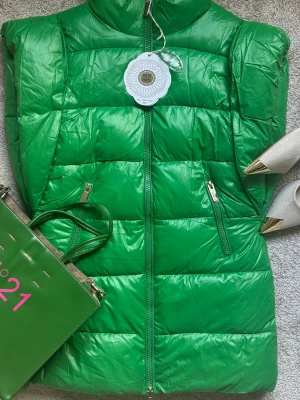 Grön dunväst med dragkedja - Snygg grön dunväst med hög krage och två dragkedjeförsedda fickor framtill. Västen har quiltad design och stängs med dragkedja. Perfekt för lager-på-lager och ger en cool look till din outfit.