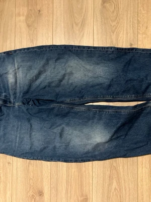 Blå raka asos jeans i klassisk modell  - Snygga blå asos jeans med raka ben och lätt slitna detaljer. Jeansen har en klassisk femficksdesign och är tillverkade i ett robust denimtyg. Perfekta för dig som gillar en tidlös och enkel stil.