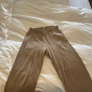 Soft Goat cashmere byxor - Mysiga beige soft goat mjukisbyxor med snörning i midjan och avslappnad passform. Perfekta för chill dagar hemma eller när du vill vara extra bekväm. Tillverkade i cashmere