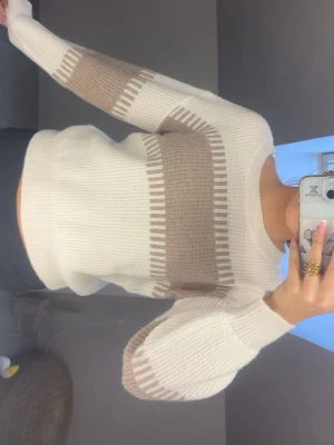 Beige och vit stickad tröja - Säljer en snygg stickad tröja i beige och vitt med breda blockränder och rund hals. Tröjan har långa ärmar och ribbade muddar. Perfekt för dig som gillar en stilren och modern look. Vet tyvärr ej logga då tröjan är gammal men så kan då sänka mitt pris 💕