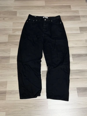 Svarta loose fit jeans - Säljer ett par svarta jeans med loose passform och raka ben. Klassisk femficksmodell med knappgylf och bälteshällor. Perfekta för en avslappnad och trendig stil.