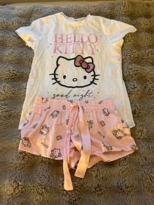 Hello Kitty pyjamas set rosa/vit - Sött pyjamasset med vit t-shirt och rosa shorts från New yorker. Tröjan är i storlek xs och shortsen i storlek xxs. Det är i bra skick och använt fåtal gånger❤️