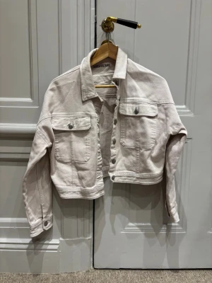 Ljusbeige croppad jeansjacka Zadig & Voltaire - Snygg ljusbeige croppad jeansjacka från Zadig & Voltaire. Klassisk modell med två bröstfickor, knappar framtill och långa ärmar. Perfekt för dig som vill ha en trendig och avslappnad look.