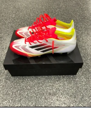 Adidas F50 PRO pris kan diskuteras  - Snabba Adidas X Speedflow fotbollsskor i vitt, rött och gult med svarta detaljer. Skorna har snörning, låg profil och är tillverkade i syntetmaterial för bästa grepp och känsla på planen. Perfekta för dig som vill dominera matchen.