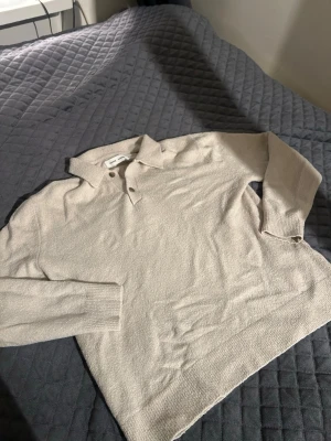 Beige pikétröja från Samsøe Samsøe - Säljer en beige pikétröja från Samsøe Samsøe med klassisk krage och två knappar framtill. Tröjan är långärmad och har en mjuk, stickad känsla som passar perfekt till lager på lager. Enkel och stilren design som funkar till det mesta.