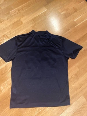 NFL tröja  - Säljer en svart sporttröja från Starter med stort vitt nummer 92 på framsidan. Tröjan har korta ärmar, V-ringad hals och är gjord i ett lätt och ventilerande syntetmaterial. Perfekt för dig som gillar sportig stil.