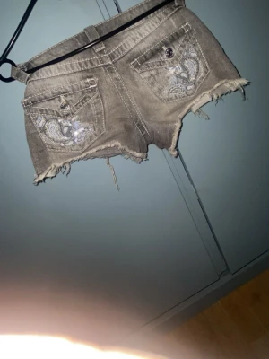 Grå jeansshorts från Gina Tricot - Säljer ett par grå jeansshorts från Gina Tricot i storlek 140. Shortsen har råa kanter nertill och klassiska fickor fram och bak. Perfekta för en avslappnad och cool stil.
