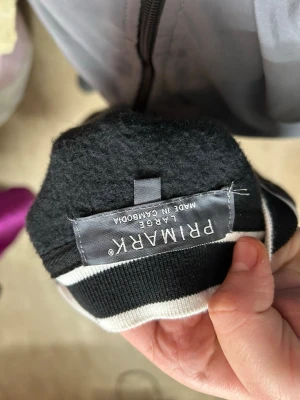 Svart baseballtröja från Primark - Svart baseballinspirerad tröja från Primark med vita ränder och knappar framtill. Tröjan har en broderad bokstav 'C' på ena sidan och ribbade muddar vid ärmslut och nederkant. Perfekt för en sportig och avslappnad stil.
