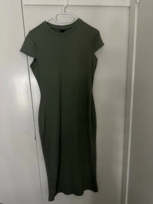 Olivgrön ribbad t-shirtklänning - Snygg olivgrön ribbad klänning med korta ärmar och rund halsringning. Modellen är kroppsnära och har en enkel, stilren design utan synliga detaljer. Perfekt för en trendig och avslappnad look. Från river island