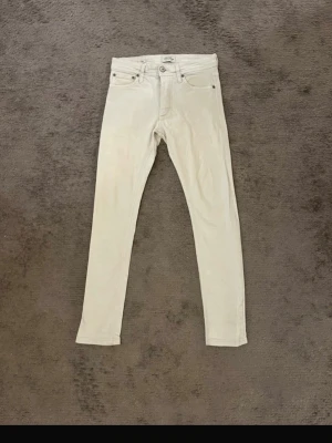 Vita slim fit jeans Jack&Jones - Snygga vita slim jeans från Jack&Jones med klassisk femficksdesign och smal passform. Jeansen har normal midja och är tillverkade i mjukt bomullstyg med stretch för extra komfort. Perfekta att styla med en oversized hoodie eller en enkel t-shirt.