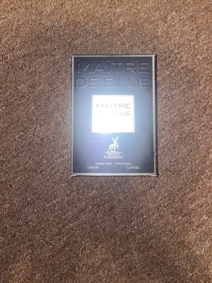 Maître De Blue parfym 100ml - Maître De Blue från Maison Alhambra är en parfym i en elegant, mörkblå fyrkantig flaska med silverdetaljer. Förpackningen är stilren och modern, perfekt för dig som gillar exklusiva dofter. Flaskan rymmer 100 ml och har en lyxig känsla.