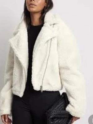 Vit croppad teddyjacka NaKd - Säljer en supermjuk och fluffig vit teddyjacka i croppad modell. Jackan har bred krage, långa ärmar och coola dragkedjedetaljer. Perfekt för dig som vill ha en trendig och cozy look till hösten eller vintern.