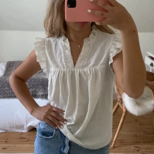 Vit topp - Supersöt vit topp med broderade detaljer, volangärmar och v-ringning med spetskant. Blusen har små diskreta prickar i tyget. Lånade bilder.