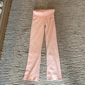 Ljusrosa yoga pants i stickat material  med ribbad midja från Gina Tricot - Supersnygga och mysiga yoga pants med stickat material. Byxorna är utsvängda där nere och är gjorda i ett mjukt material som känns riktigt bekvämt. Perfekta för myskvällar med kompisar eller mysiga dagar hemma.