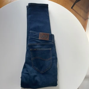 Lee Extreme Motion Slim Taper jeans - Snygga mörkblå jeans från Lee, modell Extreme Motion Slim Taper MVP. Jeansen har klassisk femficksdesign, bruna kontrastsömmar och är tillverkade i stretchigt bomullsmaterial för extra komfort. Perfekta för dig som gillar en smalare passform med avsmalnande ben. Bild skickas privat om önskas! Använda max 2 gånger 