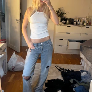 Vit ribbad linnetopp med halterneck - Säljer en vit ribbad linnetopp med halterneck och tight passform. Toppen är ärmlös och har en stilren, enkel design som passar perfekt till jeans eller kjol. Materialet är mjukt och stretchigt för en bekväm känsla. Perfekt för varma dagar eller lager-på-lager.