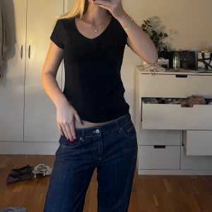 Svart v-ringad t-shirt - En svart t-shirt med v-ringning och korta ärmar. Modellen är klassisk och enkel, perfekt för en clean och stilren look. T-shirten har en normal passform och är tillverkad i mjukt bomullstyg som känns skönt mot huden.