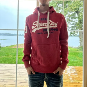 Superdry Hoodie - Röd Superdry hoodie i mycket bra skick | Storlek: S | Jag är 182cm och väger 65kg📏| Vid frågor eller diskussion om pris är det bara att skriva ✍🏼 | Frakt inom 48h📦