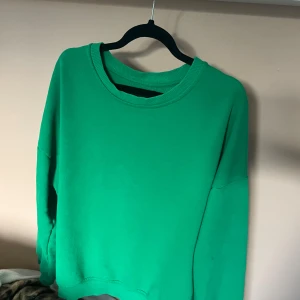 Grön sweatshirt 💘 - Säljer en enkel och stilren grön sweatshirt med rund halsringning och långa ärmar. Tröjan har en loose passform och är tillverkad i mjuk bomull, perfekt för en chill och avslappnad look. Älskar att färgen poppar, tycker mina kompsar också ❤️