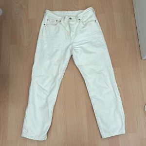 Vita Levi's 501 jeans straight fit - Snygga vita Levi's 501 jeans med klassisk rak passform och femficksdesign. Byxorna har hög midja, knappgylf och är tillverkade i kraftig bomullsdenim. Perfekta för dig som vill ha en clean och tidlös look. Ikonisk läderpatch och röd Levi's-tagg bak.