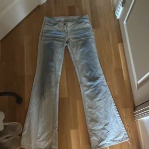Ljusblå bootcut jeans från Kookai - Säljer ett par ljusblå bootcut jeans från Kookai i storlek 38. Jeansen har klassisk femficksdesign, låg midja och är tillverkade i ett mjukt bomullsmaterial. Snygga slitningar och tvättade detaljer framtill ger en cool vintagekänsla.