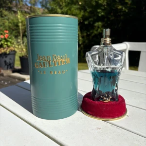 Jean Paul Gaultier Le Beau EdT 75ml kvar av 125ml flaskan - Jean Paul Gaultier Le Beau Eau de Toilette 125ml. Flaskan är formad som en manlig torso i klart glas med blågrön vätska och gulddetalj. Kommer i en stilren grön metallburk med guldfärgad text och lock. En ikonisk och snygg parfym för dig som gillar unika flaskor. Ca: 60% kvar