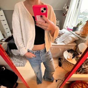 Vit stickad kofta i loose fit - Supermysig vit stickad kofta med loose passform och v-ringad öppning. Koftan har breda ärmar och är perfekt att slänga över ett linne eller t-shirt. Enkel och stilren design som passar till jeans eller kjol.