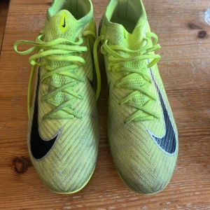 Nike Air Zoom fotbollsskor gul US10 - Säljer ett par Nike Air Zoom fotbollsskor i en riktigt skarp neongul färg med svarta detaljer och snörning. Ovandelen är i syntetmaterial med mönstrad struktur och sulan har tydliga dobbar för bra grepp på planen. Perfekta för dig som vill sticka ut på matchen! De är använda ett flertal gånger men har blivit lite missfärgade pga att de använts på gräs men inte så stora tecken på slitage. Hör av er vid frågor😁