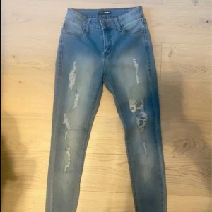 Blå skinny jeans med slitningar - Snygga ljusblå skinny jeans från Bik Bok med slitna detaljer framtill. Jeansen har klassisk femficksdesign, normal midja och är tillverkade i stretchigt denim för en tight passform. Perfekta för en avslappnad och trendig look.