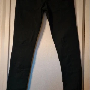 Svarta högmidjade jeans - Svarta jeans med smal passform och klassisk design. Byxorna har en enkel look och passar perfekt till en stilren outfit. Materialet är bomull och elastan. Byxorna är använda endast vid ett fåtal tillfällen. Högmidja, knäpps med dragkedja och 4 knappar. Modell: gambler hw slim  Stl 34-36.