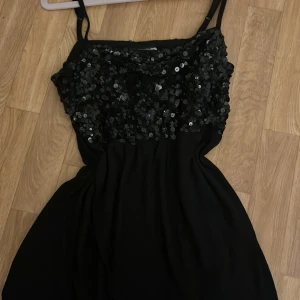 Svart paljettlinne från Lindex - Snygg svart linnetopp från Lindex med smala axelband och massor av svarta paljetter över bysten. Banden är justerbara och i midjan är det som lite insytt. Storlek M, skriv vid frågor🥰🥰