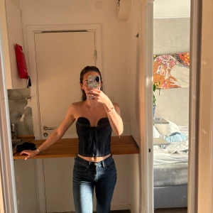 Mörkblå jeanskorsett topp - Säljer en snygg mörkblå korsett topp i jeansmaterial med markerade sömmar och hjärtformad byst. Från Zara. Xs/s