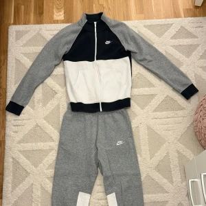 Säljer Nike Tracksuit! - Snygg zip hoodie från Nike i grått, vitt och svart. Tröjan har dragkedja, två fickor fram och klassisk Nike-logga på bröstet. Storlek: XS.