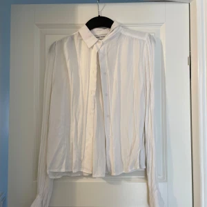 Vit skjorta från Carin Wester, stl 36 - Säljer en vit skjorta från Carin Wester i storlek 36. Skjortan har klassisk krage, knäppning framtill och långa ärmar med lätt puff vid axlarna. Materialet känns mjukt och flowy, perfekt för en clean och stilren look.