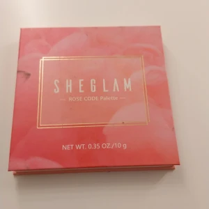 SHEGLAM Rose Code ögonskuggspalett - Snygg ögonskuggspalett från SHEGLAM med 9 olika nyanser i rosa, nude, guld och bruna toner. Paletten har både matta och skimrande skuggor med namn som Hideaway, Verve och Stiletto. Perfekt för att skapa kreativa och färgstarka looks. Förpackningen är rosa med gulddetaljer.