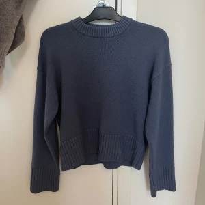 Stickad tröja  - Snygg mörkblå stickad tröja med breda ribbade muddar vid ärmslut, nederkant och halsringning. Tröjan har en avslappnad passform och är perfekt för lager-på-lager. Enkel och stilren design som funkar till allt. Slutsåld på H&M!! 