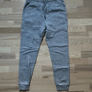 Grå mjukisbyxor från Jack & Jones XS - Grå mjukisbyxor från Jack & Jones i storlek XS. Byxorna har elastisk midja med snörning, två sidofickor och en bakficka. Tillverkade i mjukt bomullsmaterial, perfekta för chill dagar eller träning. Köpt för 699 kr 